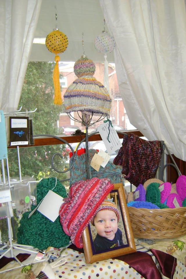 Window display of colorful hats, scarves, and hanging decorations