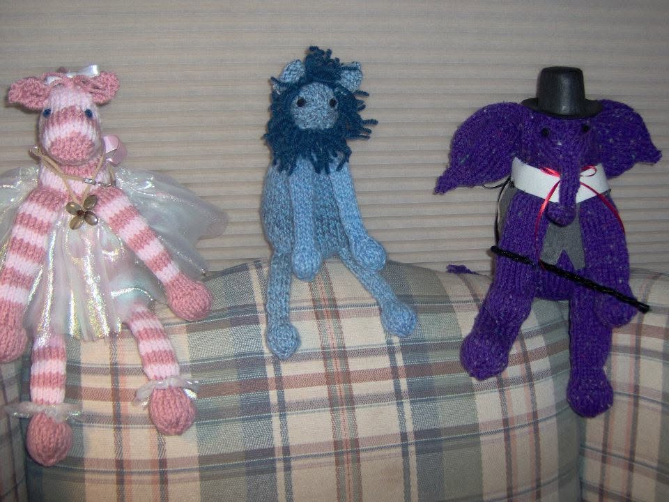 Pink, blue, and purple knitted characters on a plaid surface